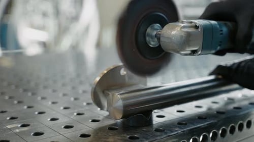 Metalworker is polishing a weld on a stainless steel tube.