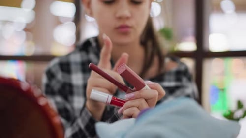 Nahaufnahme: Frau wählt Make-up-Artikel Artikel, während sie Kosmetik in der Hand beobachtet