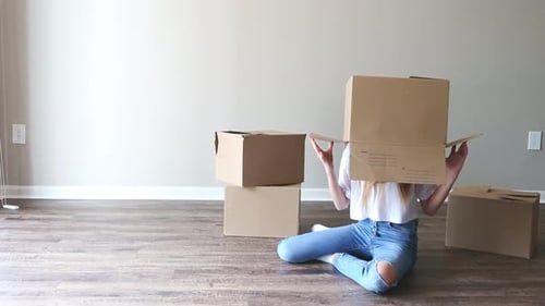 Beautiful Young Girl Moving in New House with Cardboard Boxes
