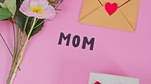 Overhead view of Mother's Day celebration setup with MOM lettering, floral decor, and wrapped