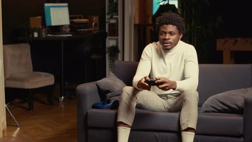 Man Plays Video Game on Couch Indoors