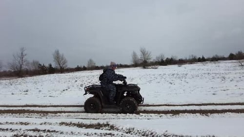 Woman Riding on a Quad Bike on a Snow Covered Path in Winter