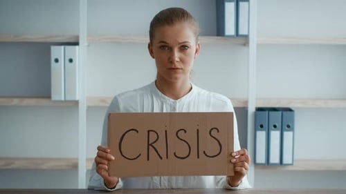 Young Businesswoman Holding Crisis Sign in Modern Office Workspace