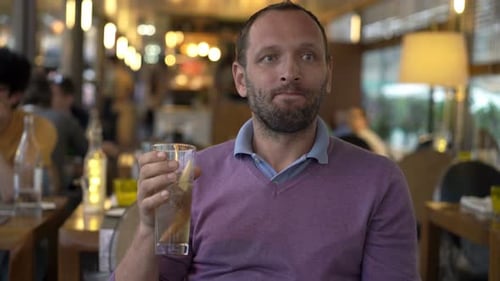 Young, Happy Man Drinking Cocktail Sitting in Cafe 30s
