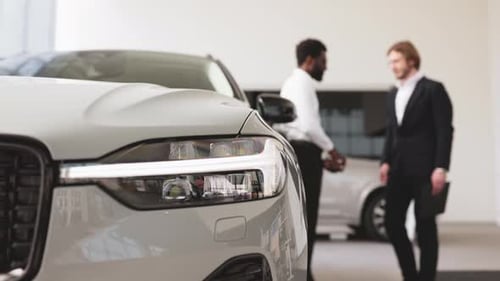 Men Shake Hands in Car Showroom