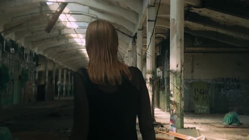 Blonde hair woman in black dress exploring abandoned industrial graffiti space mysterious atmosphere