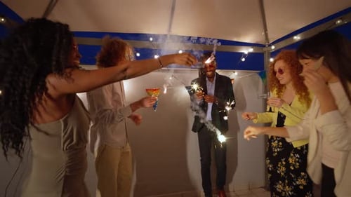 Stylish Friends Celebrating with Sparklers on Rooftop at Night