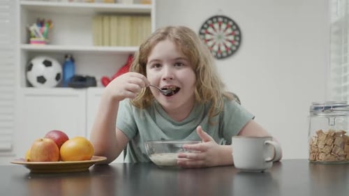 Child Eating Cereal at Table Indoors at Home