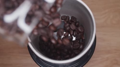 Coffee Beans Being Poured Into a Grinder