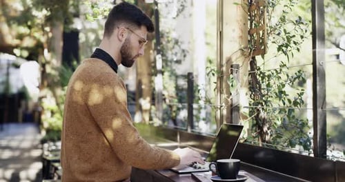 4k video footage of a young man having coffee while using his laptop at a cafe