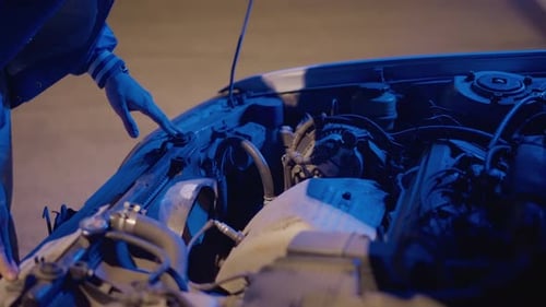 Professional Mechanic Troubleshooting Engine Under Cool Blue Glow Closeup of Car Engine Being