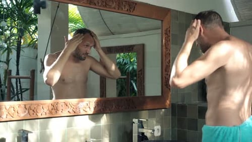 Man styling his hair in bathroom mirror
