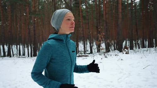 Woman Running Through Snowy Forest in Winter