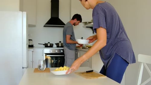 Man and Woman Preparing Food Together in Kitchen