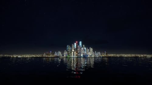 Illuminated Modern City Skyline Reflected on Water at Night