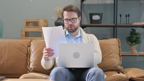 Man with Laptop and Paper on Couch