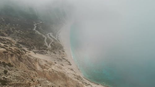 Brouillard couvrant les falaises côtières et route sinueuse près de la mer calme à Myrtos Beach en Céphalonie