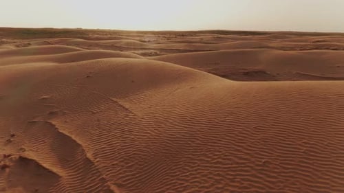 flying over the dunes in the desert at sunset, glare from the sun