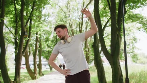 Man Stretching Before Exercising in Green Urban Park