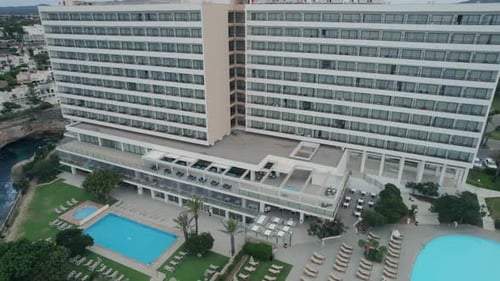 Drone aerial pan of modern hotel apartment complex design with swimming pool courtyard travel touris