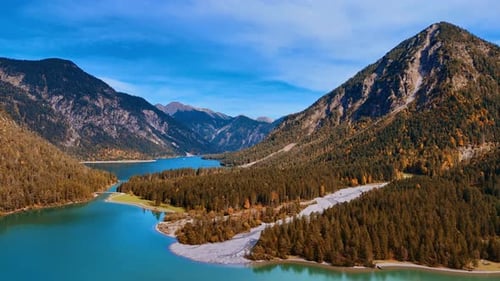 Sunlit scenery of the Alps overgrown with pine tree woods and a stunning Lake Plansee