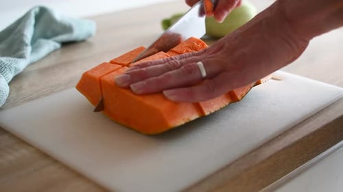 Frischen Kürbis auf einem Holzschneidebrett schneiden.