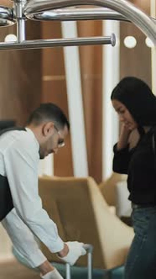 Portero masculino alegre que toma el equipaje de los huéspedes en el hotel