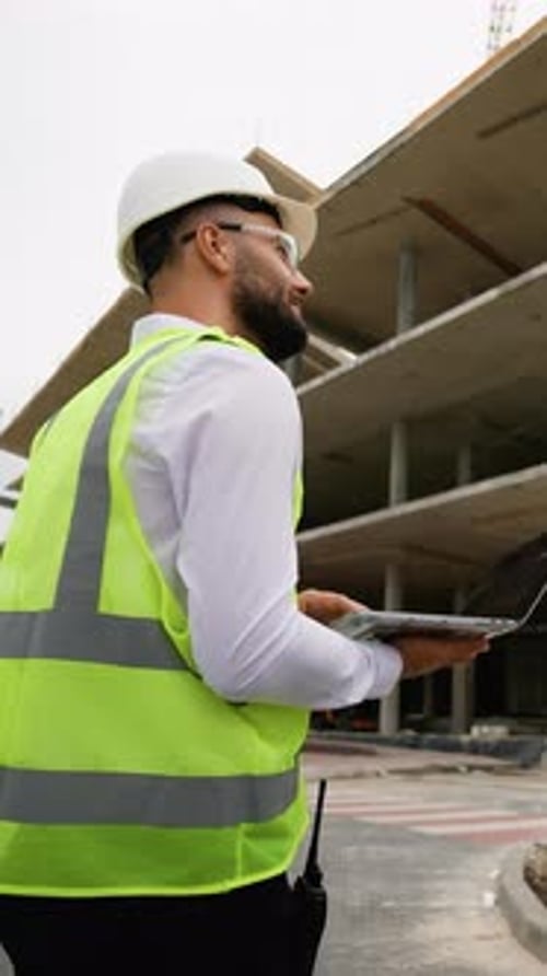 Construction Manager Supervising Building Project with Laptop
