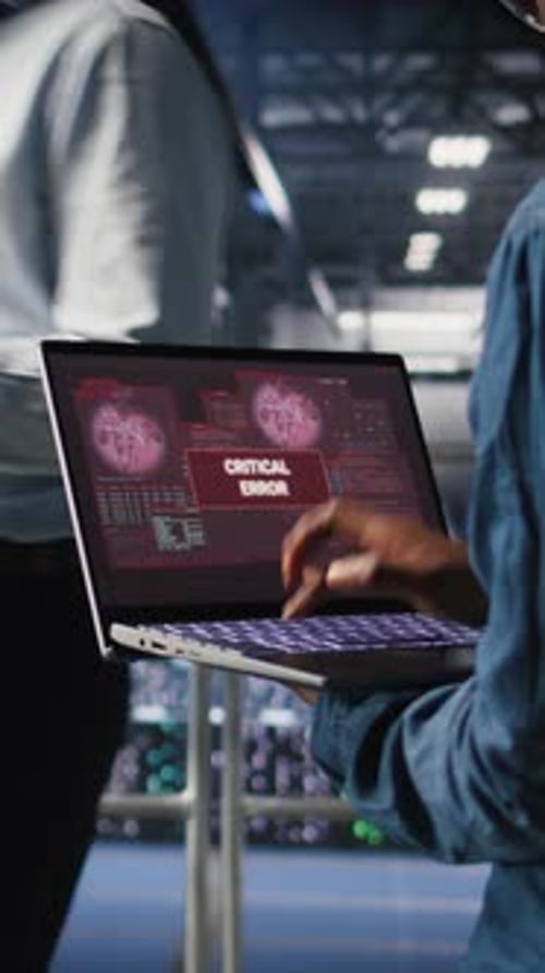 Técnico de vídeo vertical em data center estressado por um pop-up de erro crítico no laptop