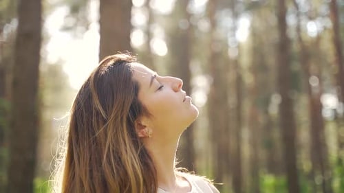 Close up portrait of a pretty young woman breathes fresh air into her full chest in the middle
