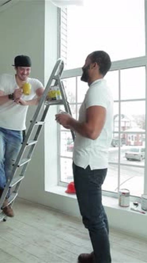 Two Workers Savor a Joyful Snack Break After Completing Repairs in a Stylish Apartment