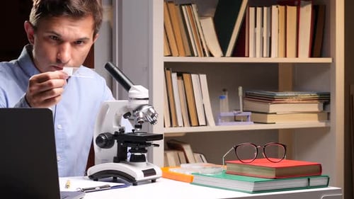 Scientist Analyzing Sample Slide in Laboratory with Microscope and Laptop