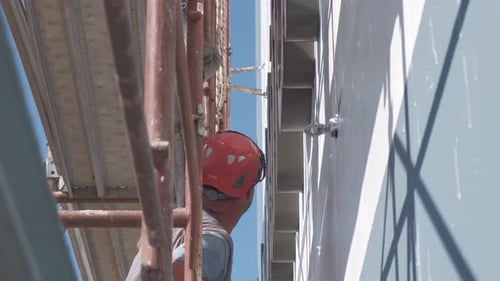 Construction Worker on Scaffolding Inspecting Building Exterior