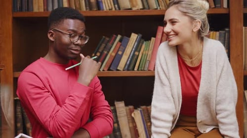 Cheerful college students studying together for exam in university library