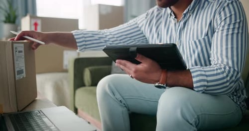 Man Using Tablet and Laptop with Boxes