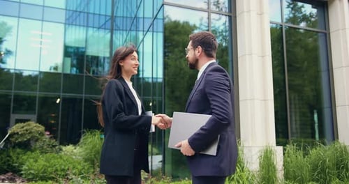 Close-up of two business partners, a man and a woman in formal suits, greeting each other