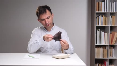 Mann untersucht eine leere Brieftasche und denkt über finanzielle Schwierigkeiten und Budgetierungsherausforderungen mit einem