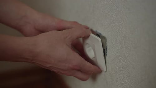 Closeup of Electrician Using Screwdriver to Install or Repair White Wall Outlet on Wall Performing