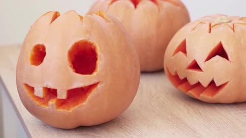 Halloween jack o lantern pumpkins on table. Handheld, dolly right