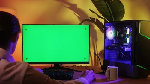 Computer mit Chroma Key, grünem Bildschirm auf dem Monitor, Gamer Man spielt in beliebten Videospielen, Programmierer
