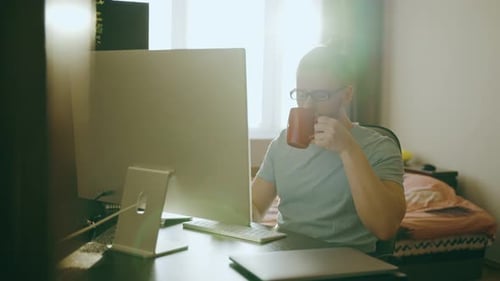 Concentrated Freelancer Guy in Glasses Looks at Computer Monitor Works at Home