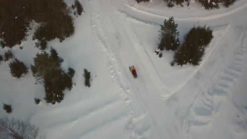Riding snowmobiles in forest on a winter day. Clip. Aerial view of a lonely traveler