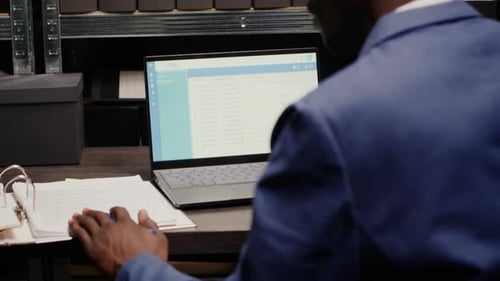 Adult Working at Desk with Laptop and Binder