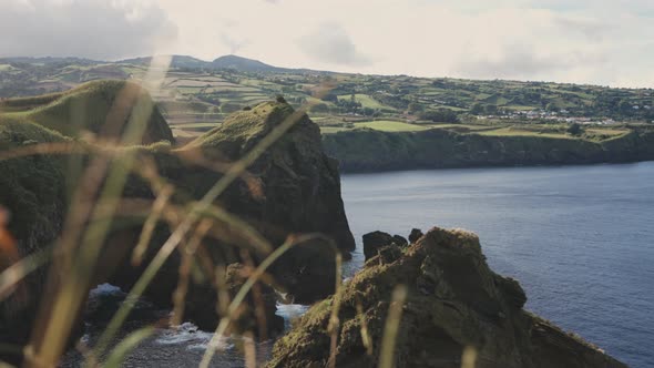Reveal pan of rural green coastal landscape and sea at the Azores ...
