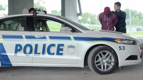 Police Officer Arresting Man Next to Patrol Car
