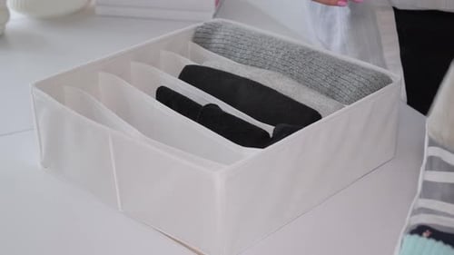 Folding Clothes into Storage Container for Home Organization