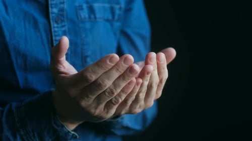 Hands in Prayer Position Against Dark Background