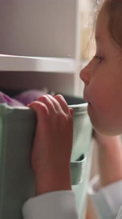 Une petite fille regarde à l'intérieur de grands contenants sur un support en bois