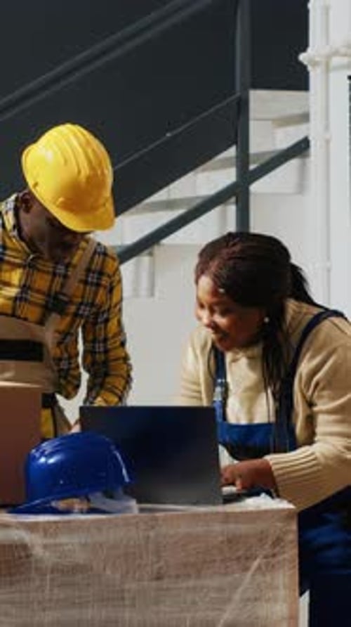 Construction Workers Conferring at Table with Laptop
