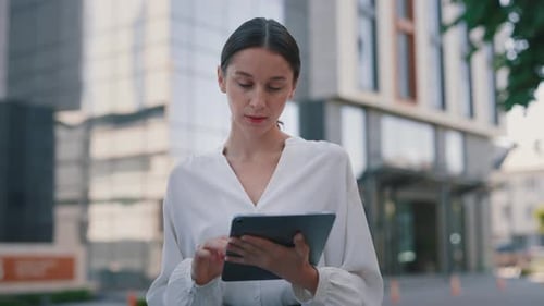 Woman Works on Tablet Outside in City